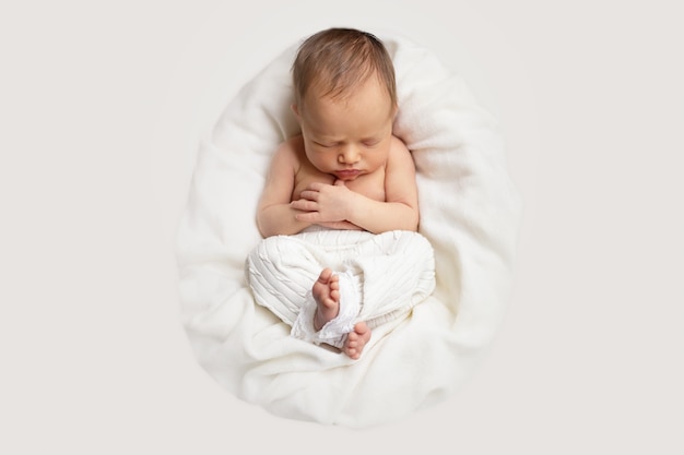 Het pasgeboren babymeisje slaapt in de mand op een witte deken en een licht