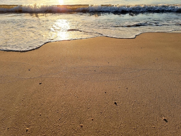 Het perspectief van de zeegolven die het zand van de strandreflectie raken met de zon