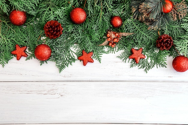 Het pijnboomblad met rode ster en Kerstmisbaldecoratie op een witte houten raad