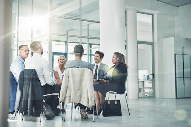 Het plannen van hun bedrijfscursus. Shot van een groep collega's die samen praten terwijl ze in een kring in een kantoor zitten.