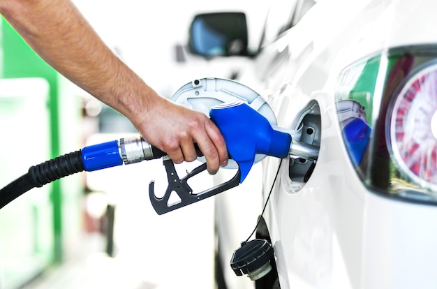 Het pompen van gas bij benzinepomp. Close-up van de mens die benzine in auto bij benzinestation pompt.