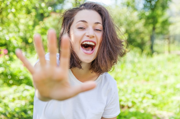 Het portret jonge gelukkige positieve lachende donkerbruine vrouw van de schoonheid op park of tuin