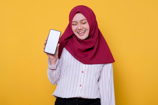 Het portret van aziatische mooie vrouw die hijab draagt, brengt een mobiele telefoon heeft pret en lacht haar ogen dicht