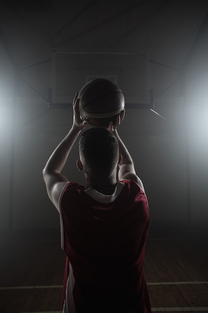 Het portret van basketbalspeler ziet uit op de rug die voorbereidingen treft te scoren