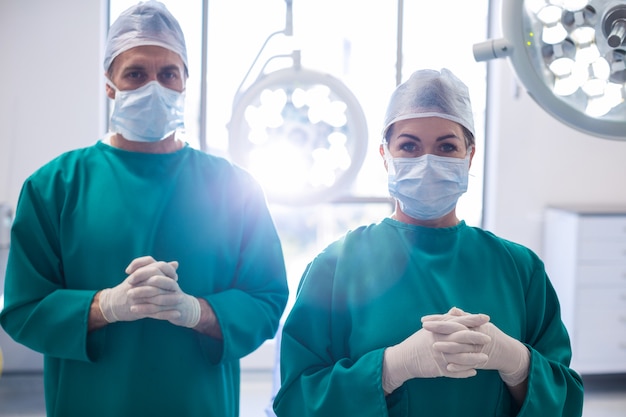 Het portret van chirurgen die zich met handen bevinden clasped in verrichtingsruimte
