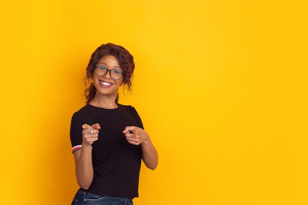 Het portret van de Afro-Amerikaanse mooie jonge vrouw op geel,