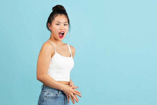 Het portret van de Aziatische jonge vrouw op blauwe studiomuur