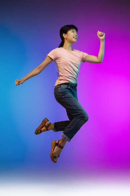 Het portret van de Aziatische jonge vrouw op de muur van de gradiëntstudio in neon