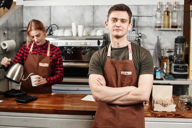 Het portret van de man-barista's op de werkplek op de achtergrond van koffie