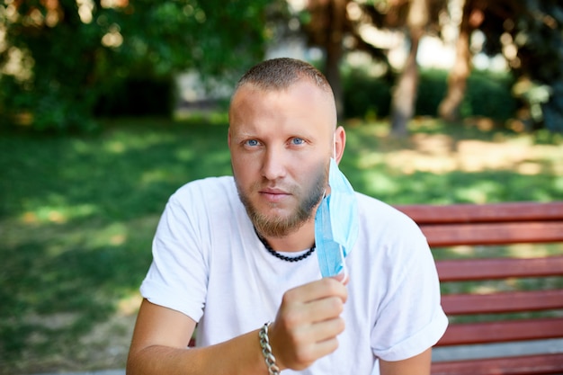 Het portret van de mens stijgt beschermend masker in het park openlucht in de stad op