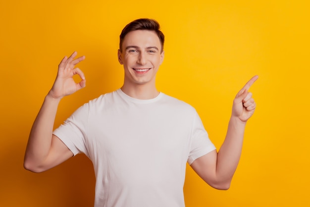 Het portret van de positieve kerel geeft aan dat de lege ruimte van de wijsvinger een goed teken op een gele achtergrond toont