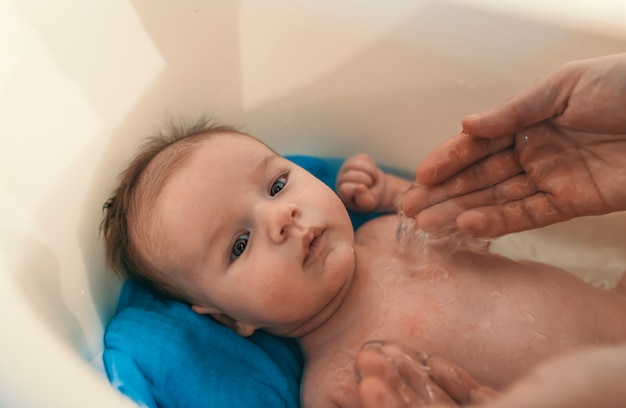 Het portret van een baby wordt gebaad door zijn vader die ton thuis gebruikt