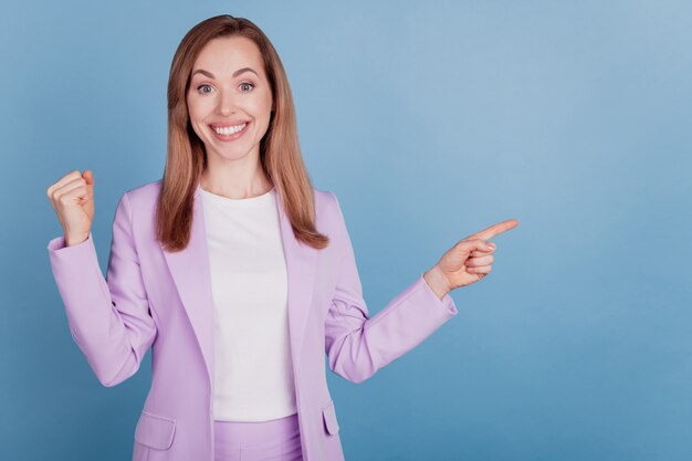 Het portret van een elegante, vrolijke vrouw die naar een lege ruimte wijst, heft het concept van de vuistwinnaar op