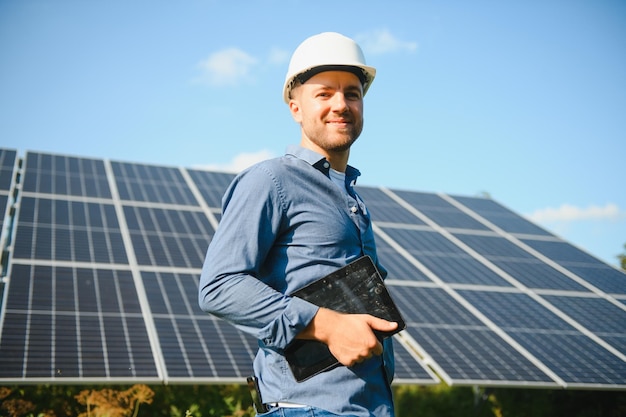 Het portret van een jonge ingenieur controleert met tabletwerking met zonreinheid op veld van fotovoltaïsche zonnepanelen Concept hernieuwbare energietechnologie elektriciteitsservice groene stroom