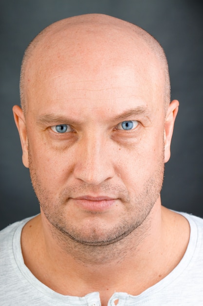Het portret van een kale mens met blauwe ogen sluit omhoog