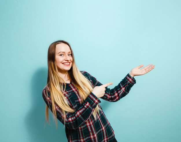 Het portret van een mooi jong meisje die gebaren tonen en is gelukkig over blauwe achtergrond