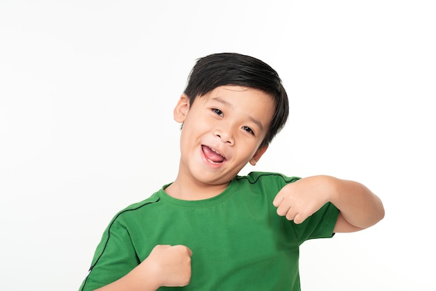 Het portret van een schattige, slimme jonge Aziatische jongen toont een winnend gebaar en glimlacht naar de camera en viert de succesoverwinning tegen wit