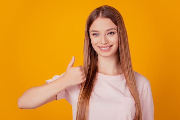 Het portret van een vrolijke positieve aardige dame steekt de duim omhoog en keurt je keuze goed op een gele achtergrond