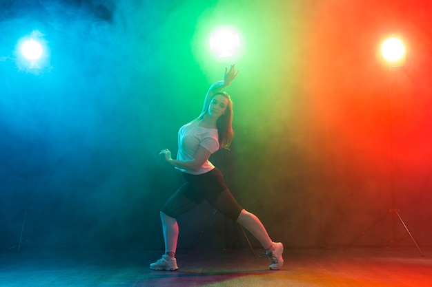 Het portret van gemiddelde lengte van slanke jonge vrouw die jazz-funk danst.