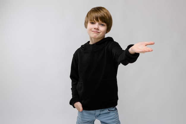 Het portret van het aanbiddelijke smilling kleine jongen bevinden die aanbiedend zijn hand met dient zak op grijs in