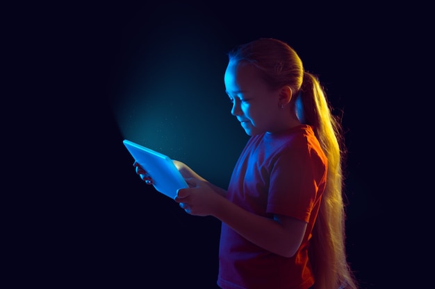 Het portret van het blanke meisje geïsoleerd op een donkere studioachtergrond in neonlicht