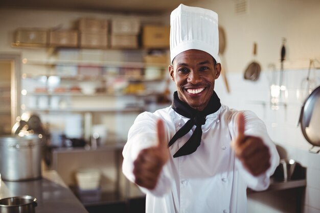 Het portret van het glimlachen chef-kok het tonen beduimelt omhoog