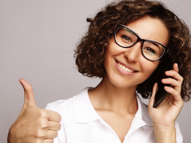 Het portret van het glimlachen het bedrijfsvrouwentelefoon spreken en toont ok