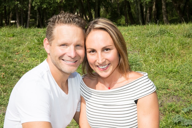 Het portret van het houden van van jong paar zit op het groene park van de grastuin