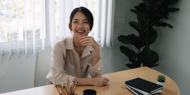 Het portret van het mooie Aziatische meisje glimlachen gelukkig stelt op haar kantoor