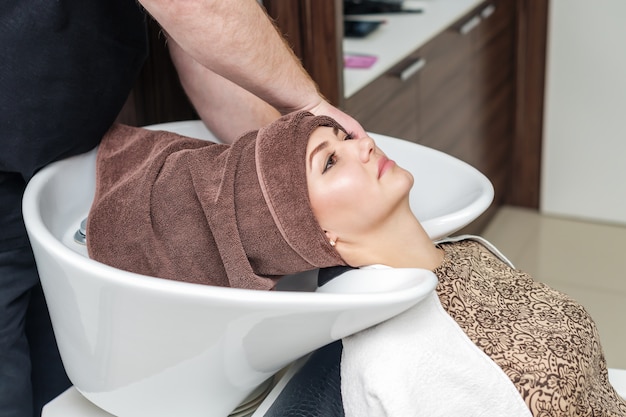 Het portret van jonge vrouw droogt haar met handdoek in schoonheidssalon.