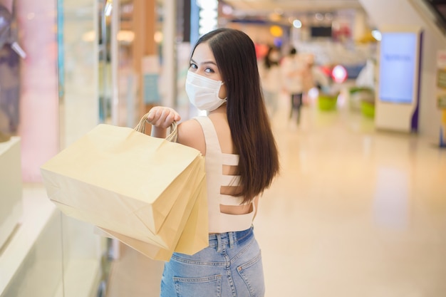 Het portret van mooie vrouw draagt gezichtsmasker in winkelcentrum