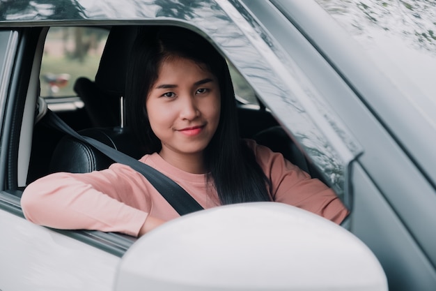 Het portret van vrouw glimlacht terwijl het drijven van een auto.