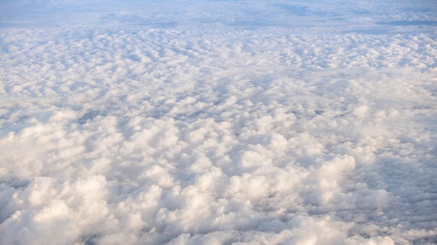 Het prachtige wolkenlandschap met heldere blauwe lucht. Panorama boven witte wolken zoals gezien door het raam van een vliegtuig. Een uitzicht vanuit het vliegtuigraam