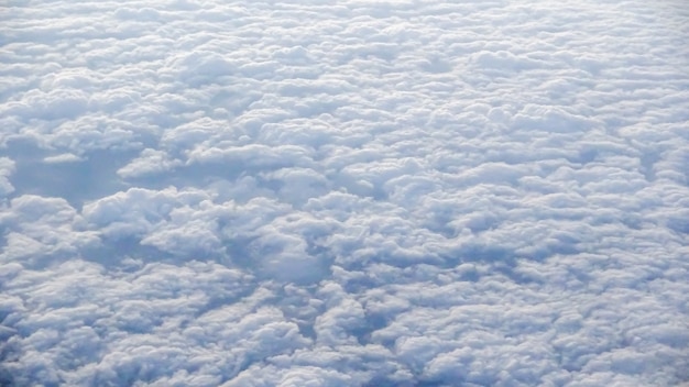 Het prachtige wolkenlandschap met heldere blauwe lucht. Panorama boven witte wolken zoals gezien door het raam van een vliegtuig. Een uitzicht vanuit het vliegtuigraam