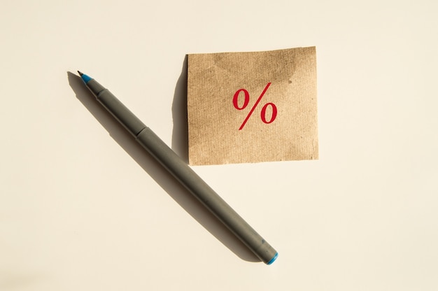 Het procentteken is geschreven op bruin inpakpapier, ernaast staat een pen, het concept van verkoop en kortingen.