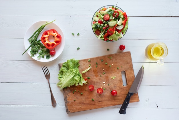 Het proces om salade thuis op een witte achtergrond te maken. Vegetarisme. Gezonde levensstijl.