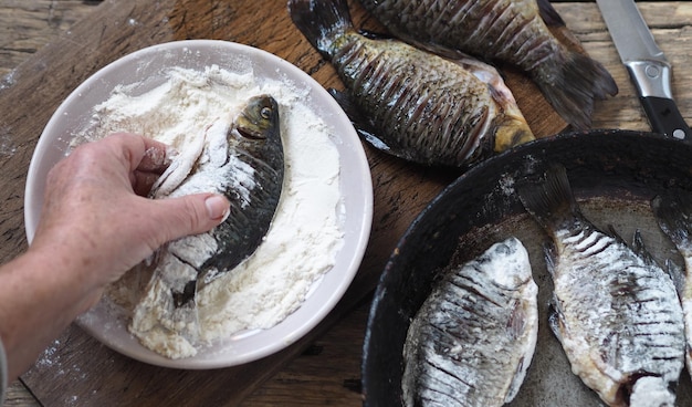 Foto het proces van het bakken van riviervis crucian karper in een zwarte pan