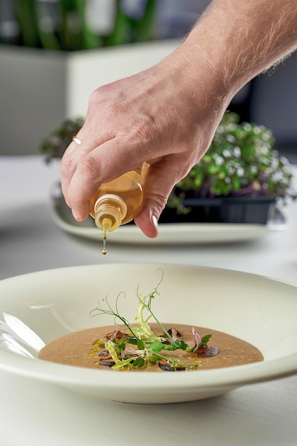 Het proces van het decoreren van de champignonroomsoep Chef legt kruiden en champignons op een bord