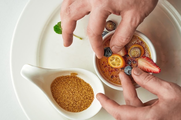 Het proces van het decoreren van een crème brulee dessert met fruit