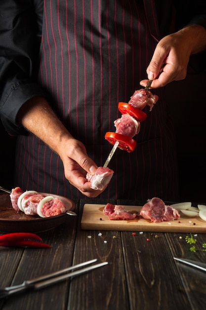 Het proces van het koken van shish kebab van rauw lamsvlees in de keuken met de handen van een chef-kok