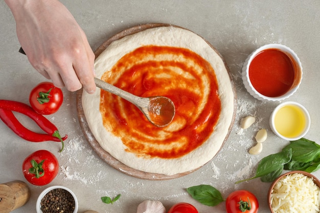 Het proces van het maken van margarita-pizza Mannelijke handen bovenaanzicht Tomatenpuree met kaas