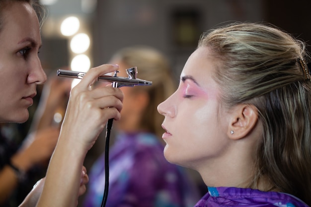 Foto het proces van het maken van moderne make-up met airbrush. visagist creëert en concentreert zich