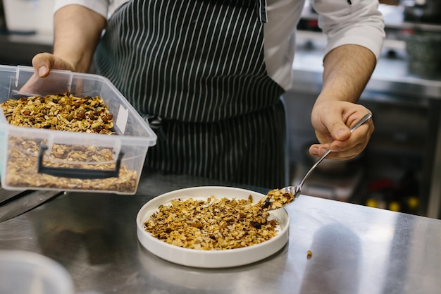 Het proces van het maken van muesli in een restaurant, een mannelijke chef-kok werkt in de keuken