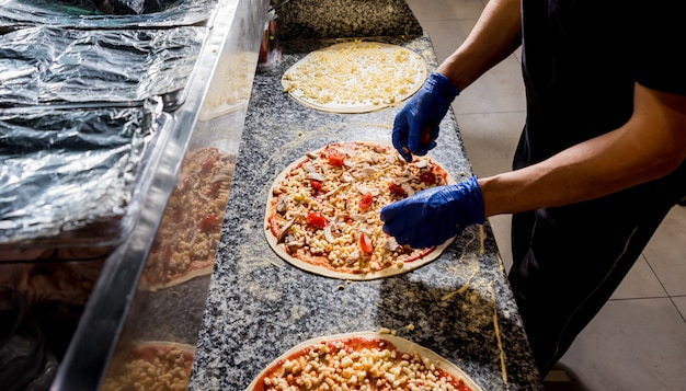 Het proces van het maken van pizza. Handen die van chef-kokbakker pizza maken bij koffiekeuken