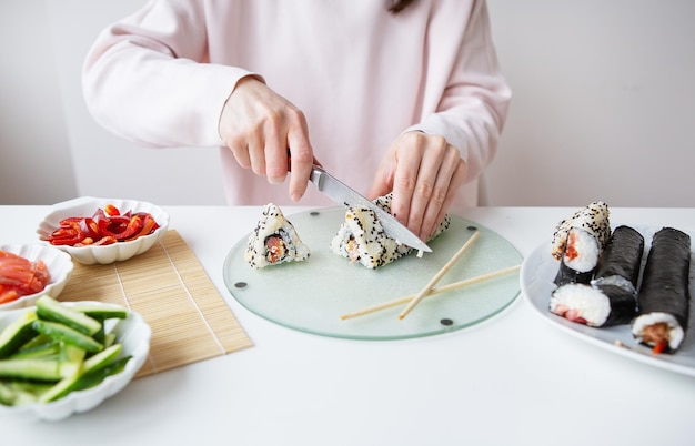 Het proces van het maken van sushi het meisje maakt sushi met verschillende smaken verse zalm kaviaar avocado komkommer gember rijst Snijd de rol in stukjes