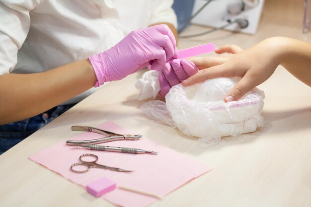 Het proces van manicure Roze handschoenen steriel instrument Vrouwelijke handenxA