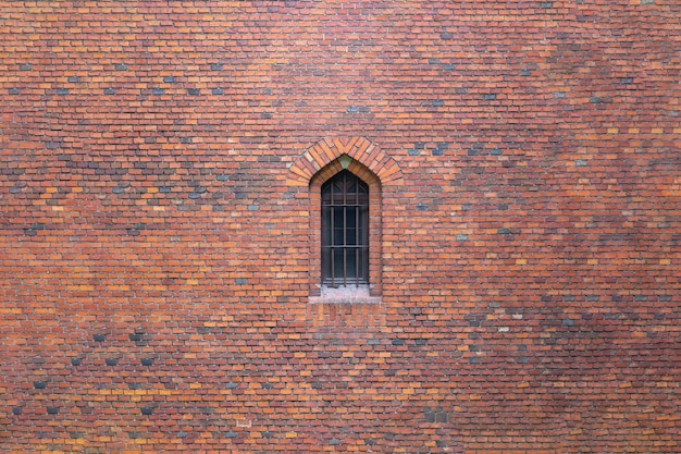 Het raam van het oude kasteel wordt afgesloten door een metalen rooster in een bakstenen muur