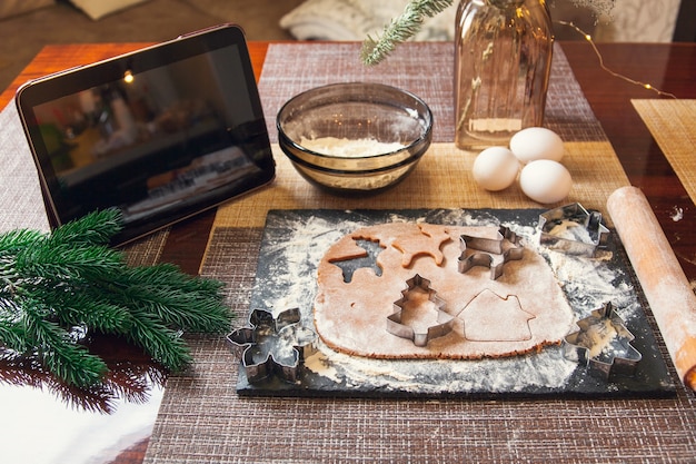 Het recept volgen op een digitale tablet - uit het deeg snijden met een mal voor het maken van kerstpeperkoek.