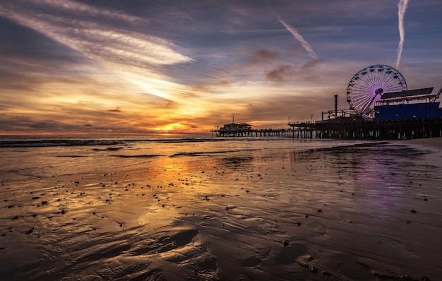 Het reuzenwiel op het strand tegen de hemel tijdens de zonsondergang