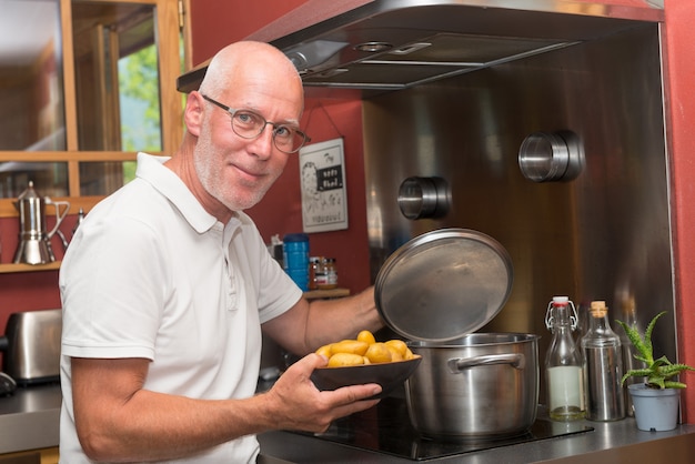 Het rijpe knappe mens koken in huiskeuken